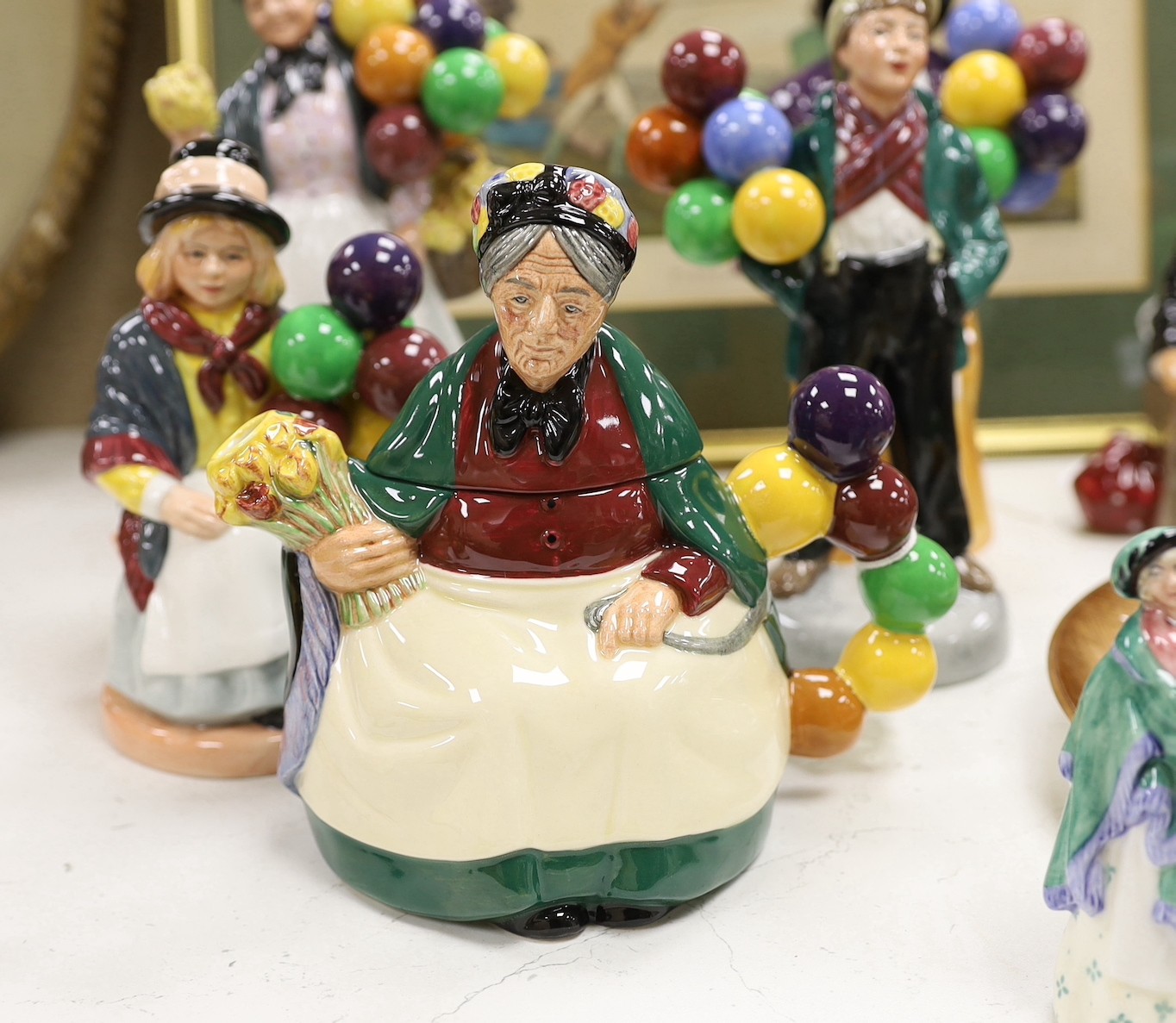 Seven Royal Doulton balloon seller figures in various sizes, a similar teapot and a dish (9), tallest Biddy Penny Farthing, 22cms high